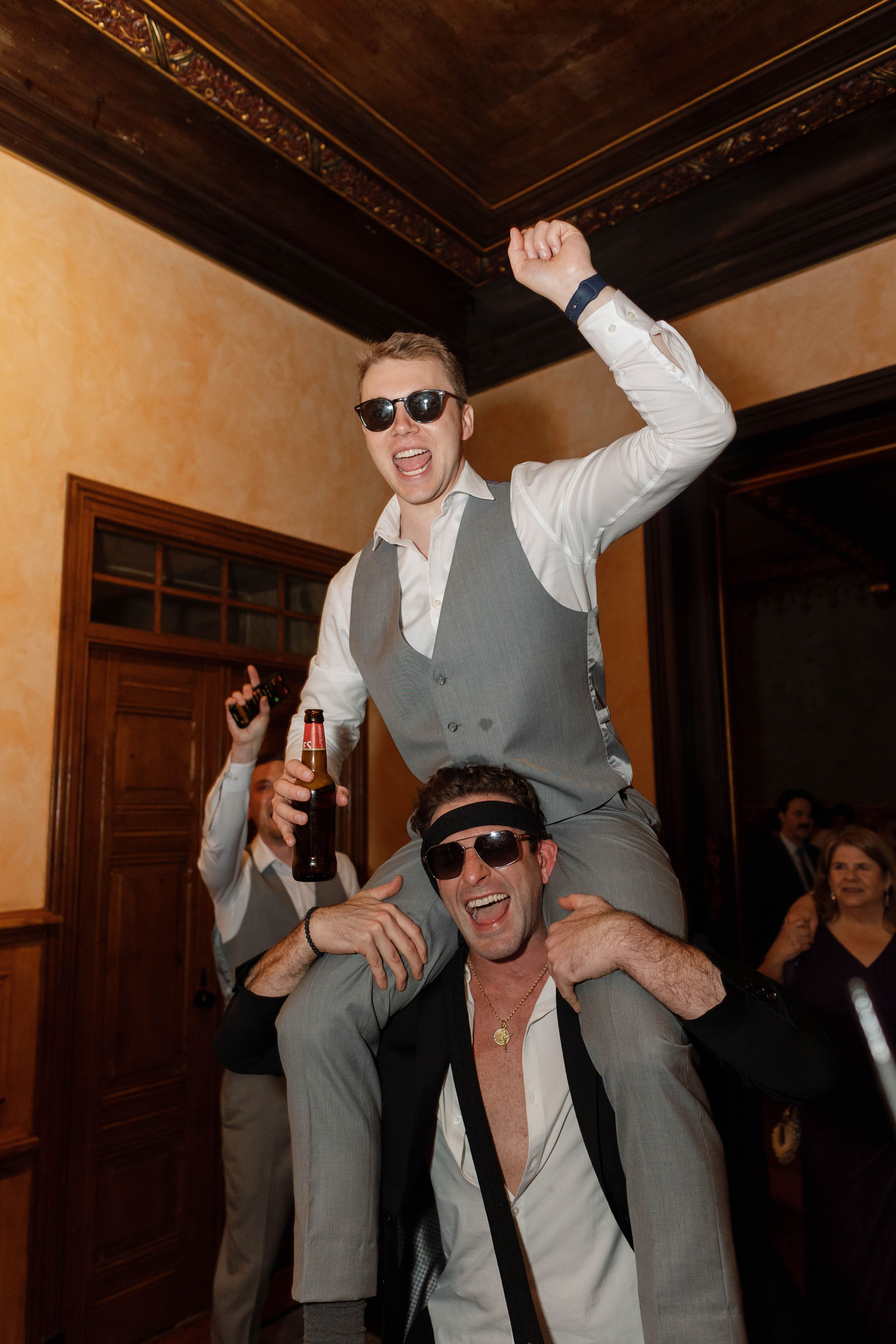 Groom carried by the shoulders of a male wedding guest as they celebrate the party of their destination wedding in Portugal