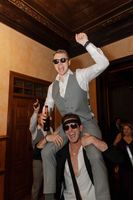 Groom carried by the shoulders of a male wedding guest as they celebrate the party of their destination wedding in Portugal
