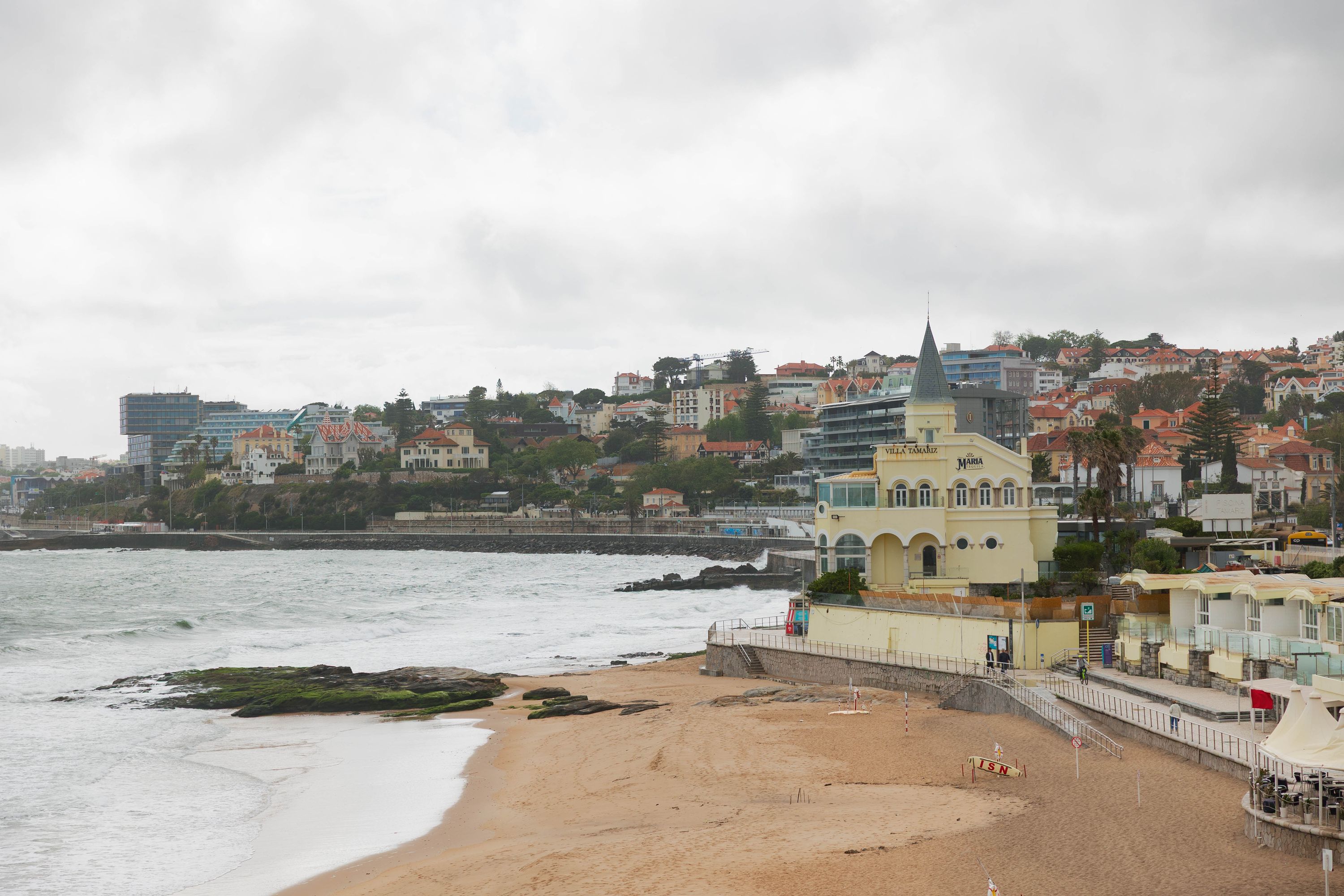 A seaside scenery consisting of coastal buildings and a large pointed castle with gray roofs