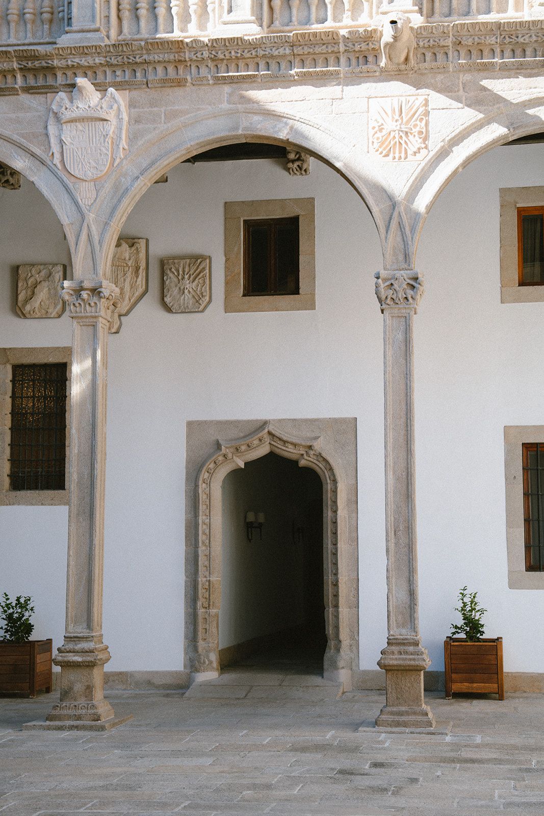 Carved royal coats of arms and a Gothic doorway in the Renaissance cloister of the Hostal dos Reis Católicos, Santiago.
