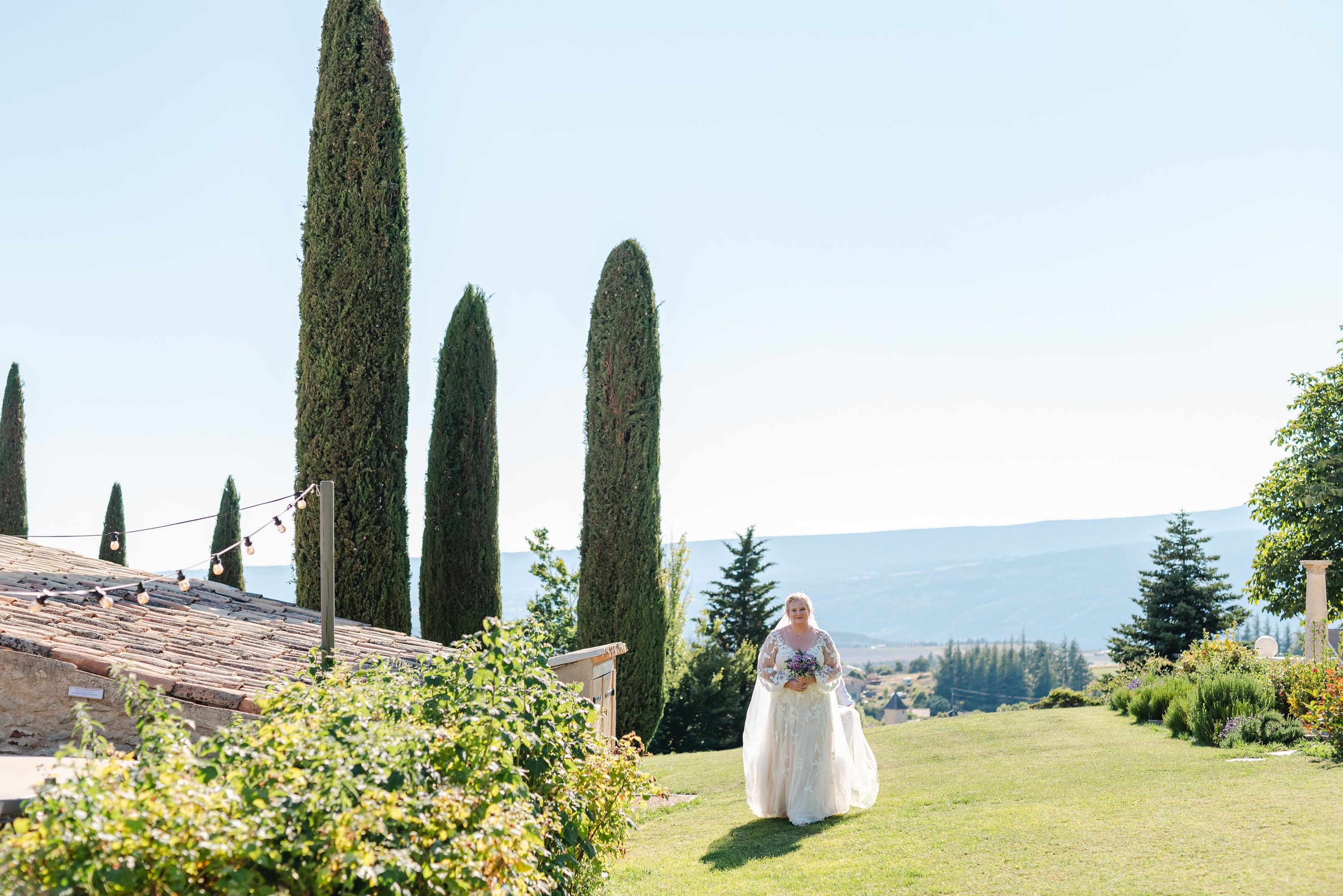 Bride walking across a garden lawn with mountain views during a small wedding in France