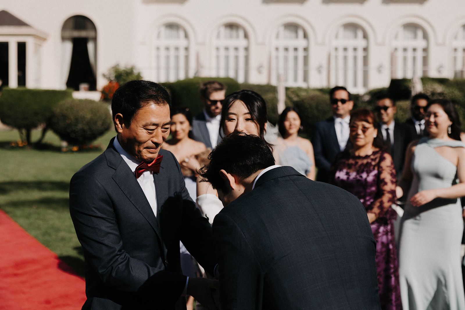 A groom holding the hand of the emotional bride's father