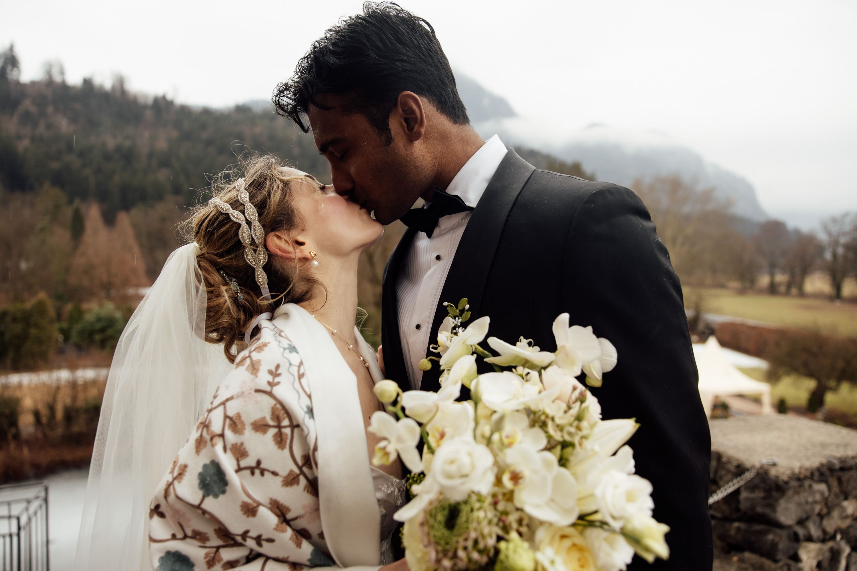 Romantic portrait of newlyweds kissing with alpine scenery at a small wedding in Austria