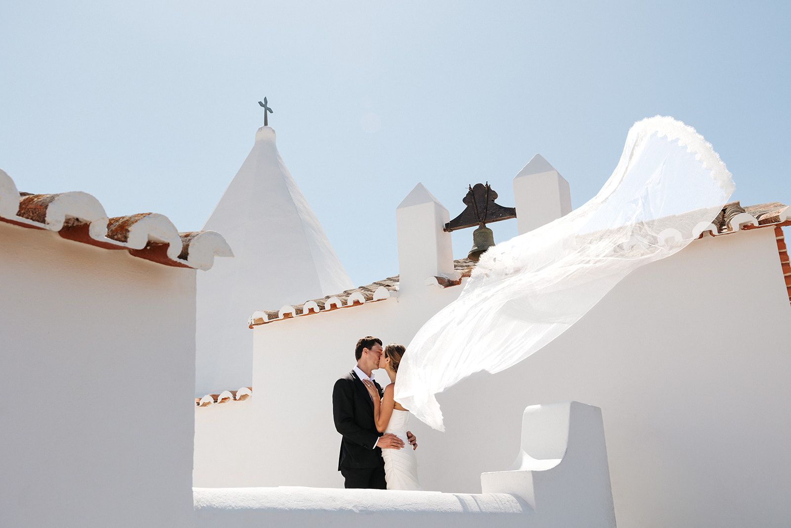 Newlyweds having a photoshoot atop the balcony of an ancient chapel during their destination wedding in Portugal