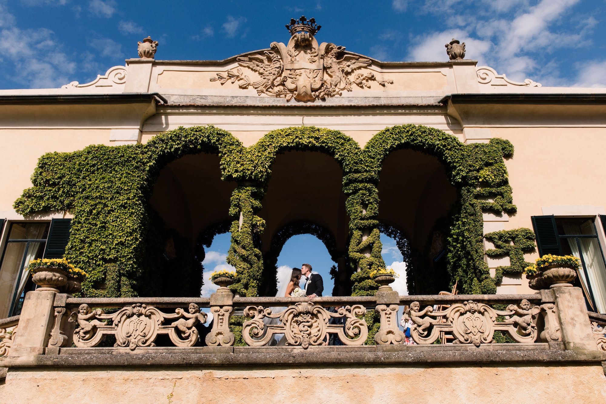 Groom kissing bride's forehead atop a terrace of an old castle in Italy