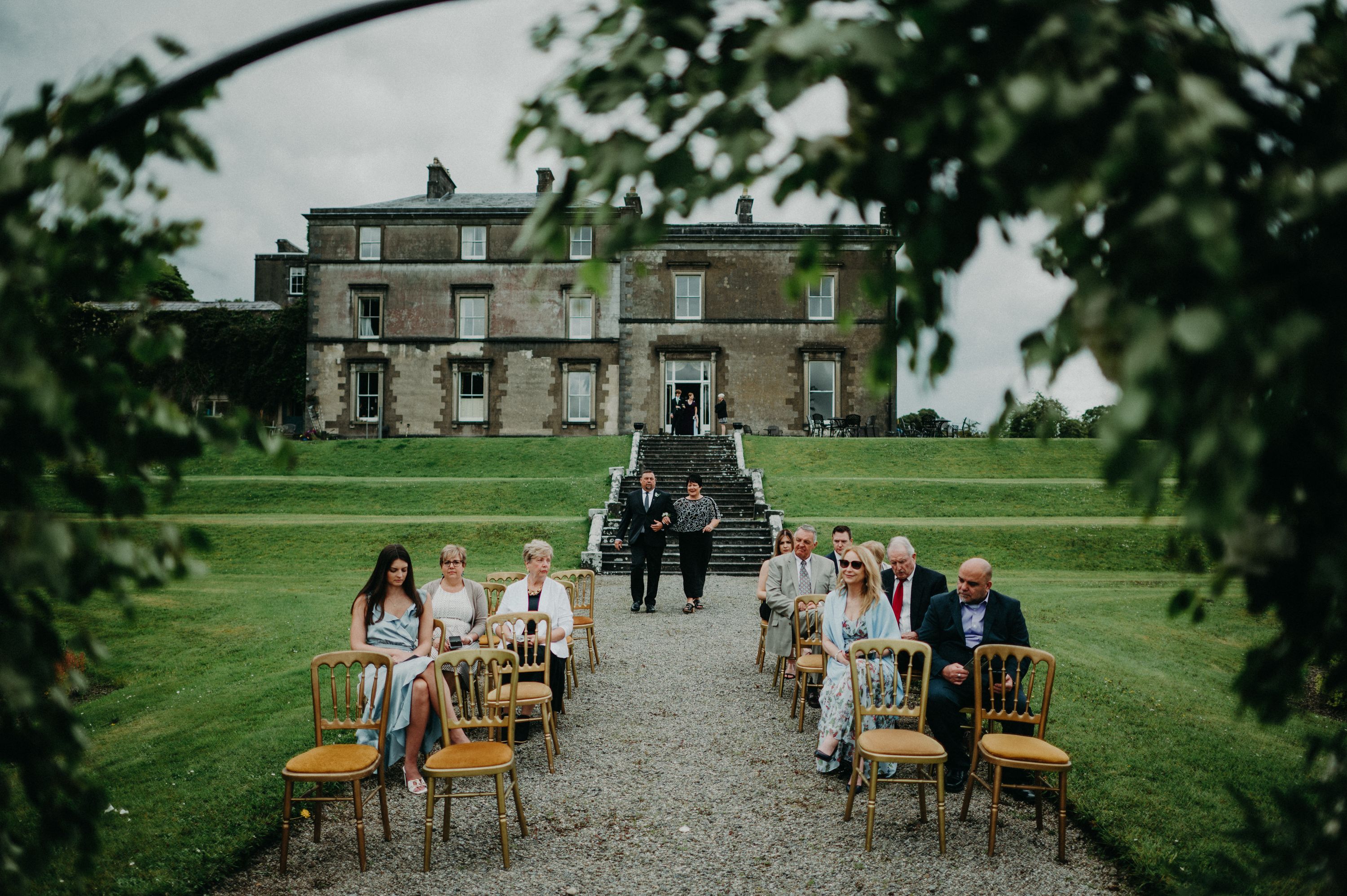 Guests gathered in a park in front of a mansion during a ceremony of a destination wedding in Ireland 