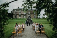 Guests gathered in a park in front of a mansion during a ceremony of a destination wedding in Ireland 