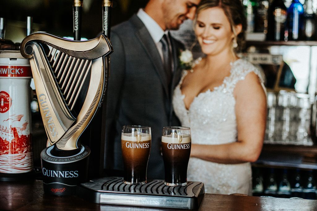 Bride and groom in front of a symbolic harp inside a traditional Irish pub celebrating their destination wedding in Ireland