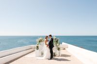 Newlyweds standing in front of their wedding arch on the cliffs after the ceremony of their Portuguese destination wedding