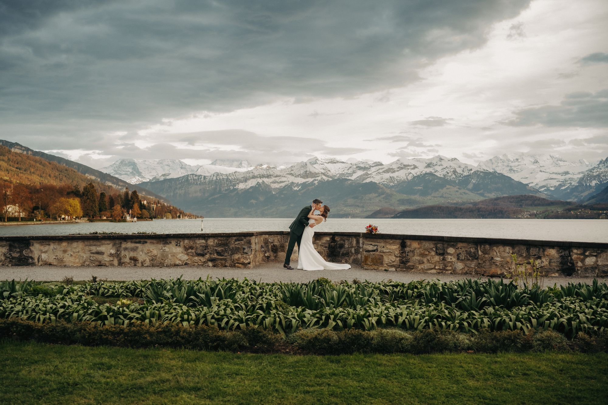 Newlyweds kissing in front of a lake and the Alps in Switzerland