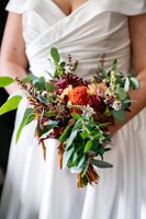 Bride's arms and hands hold a bouquet with autumn colors during her elopement in Ireland