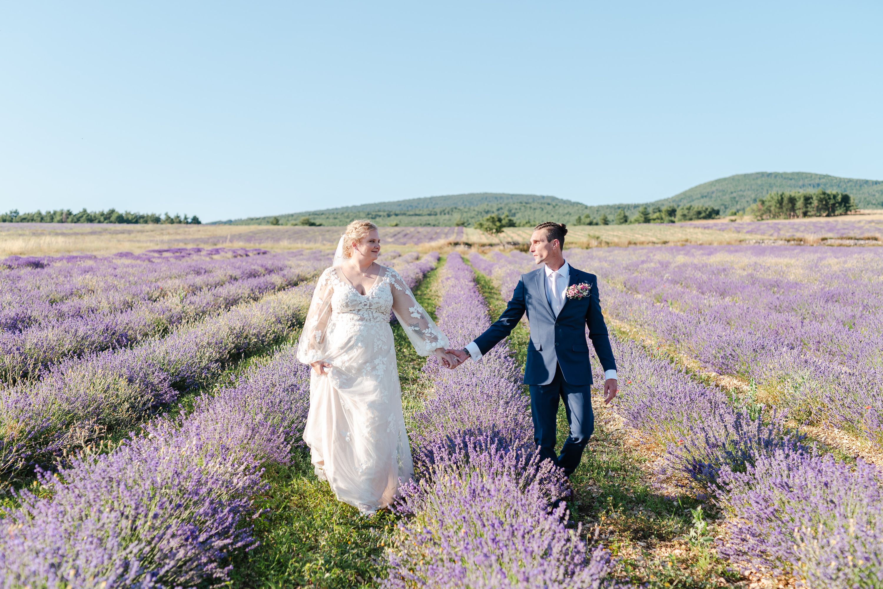 Couple walking hand in hand through lavender fields after a small wedding in France
