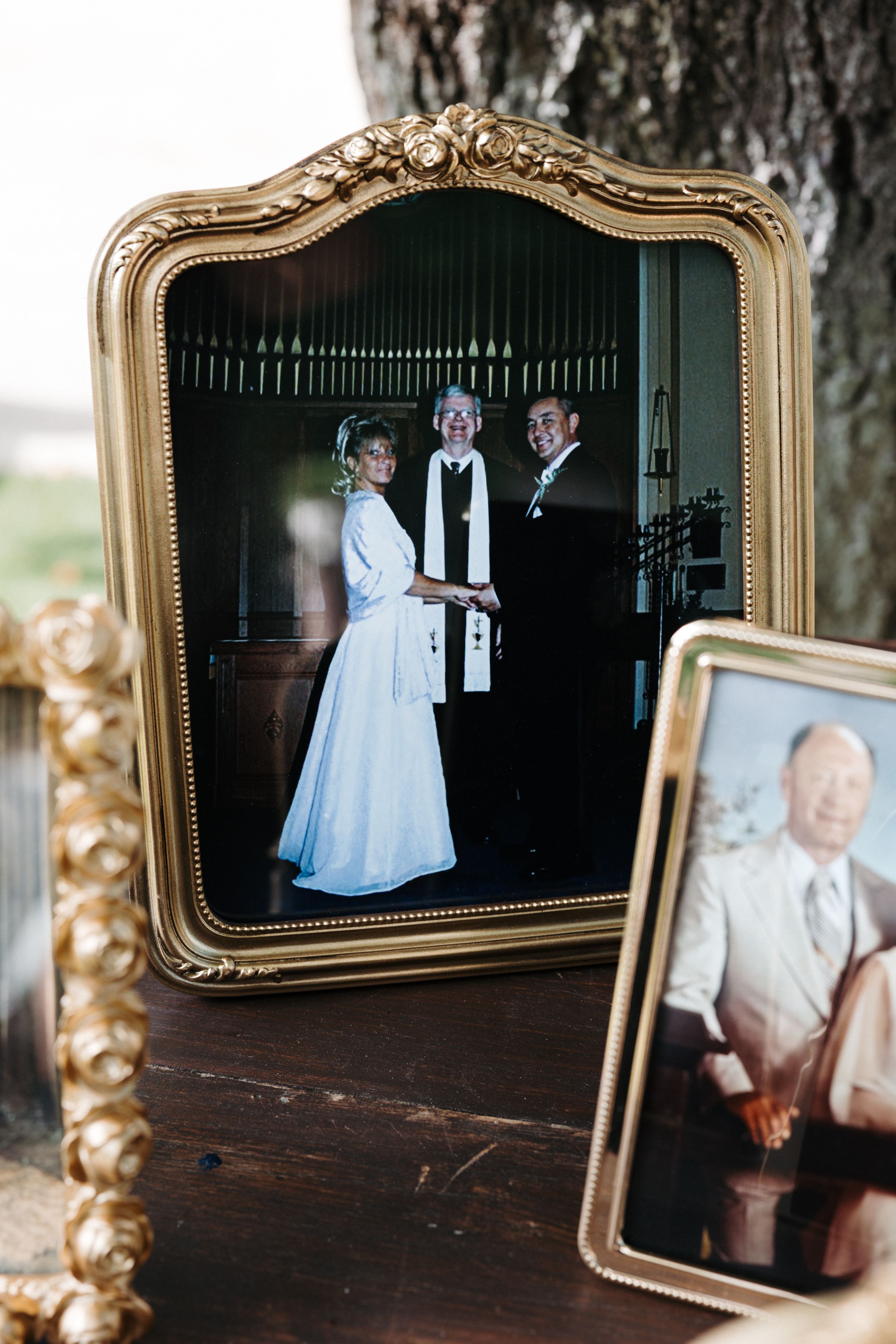A framed photo of the bride and groom looking at the camera with their celebrant during a wedding