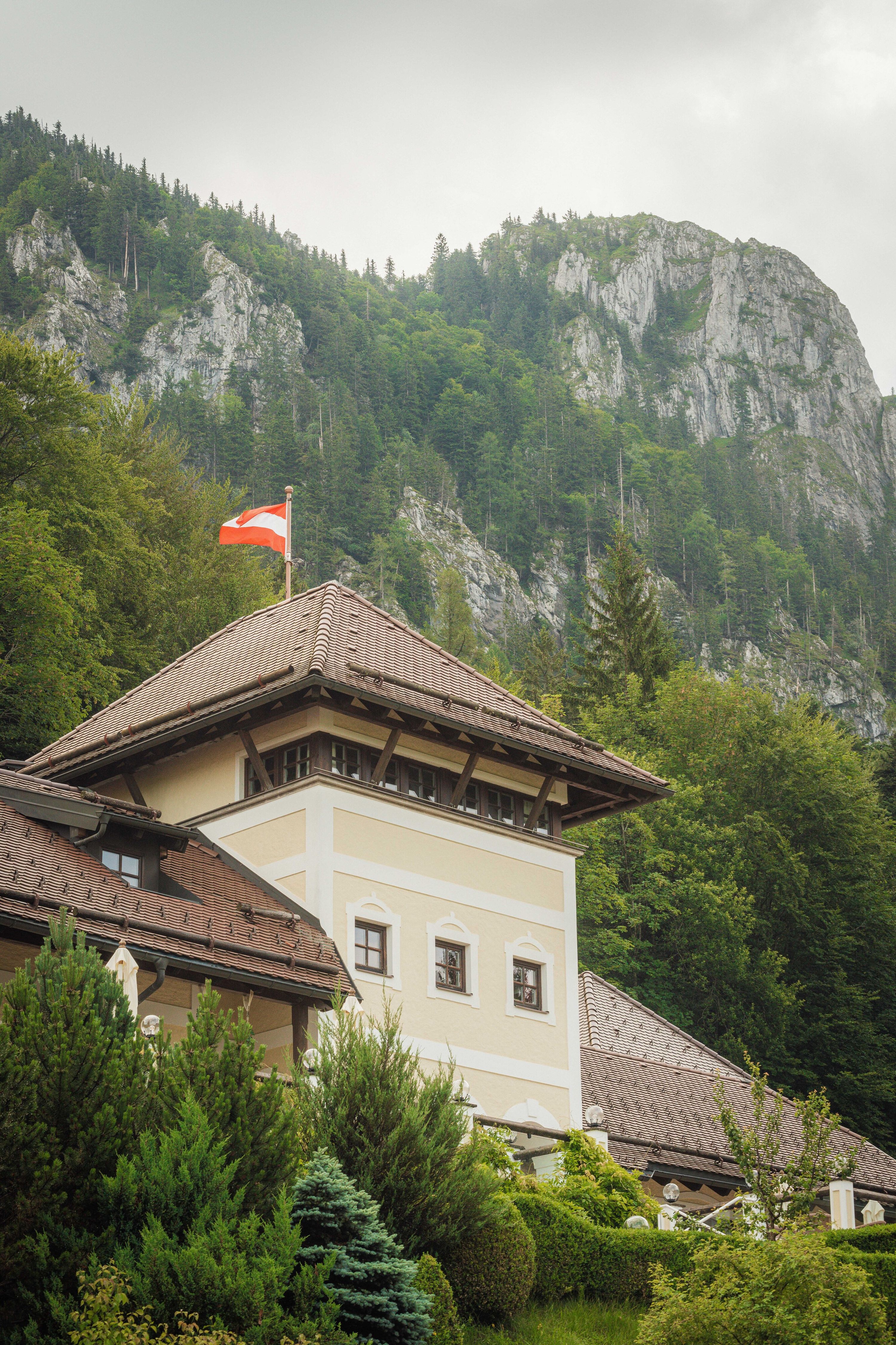 Guesthouse tower flying the Austrian flag beneath forested cliffs in the lake district