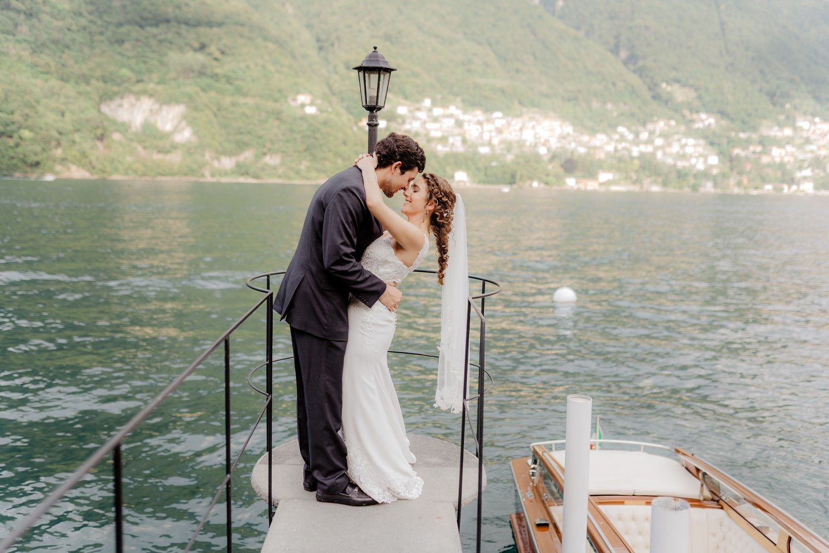 Bride and groom kissing at a wooden platform atop Lake Como during their elopement in Italy