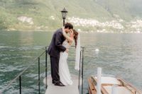Bride and groom kissing at a wooden platform atop Lake Como during their elopement in Italy