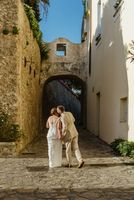 Groom kisses his bride on the temple during the photoshoot of their elopement in Italy with a medieval building in the background