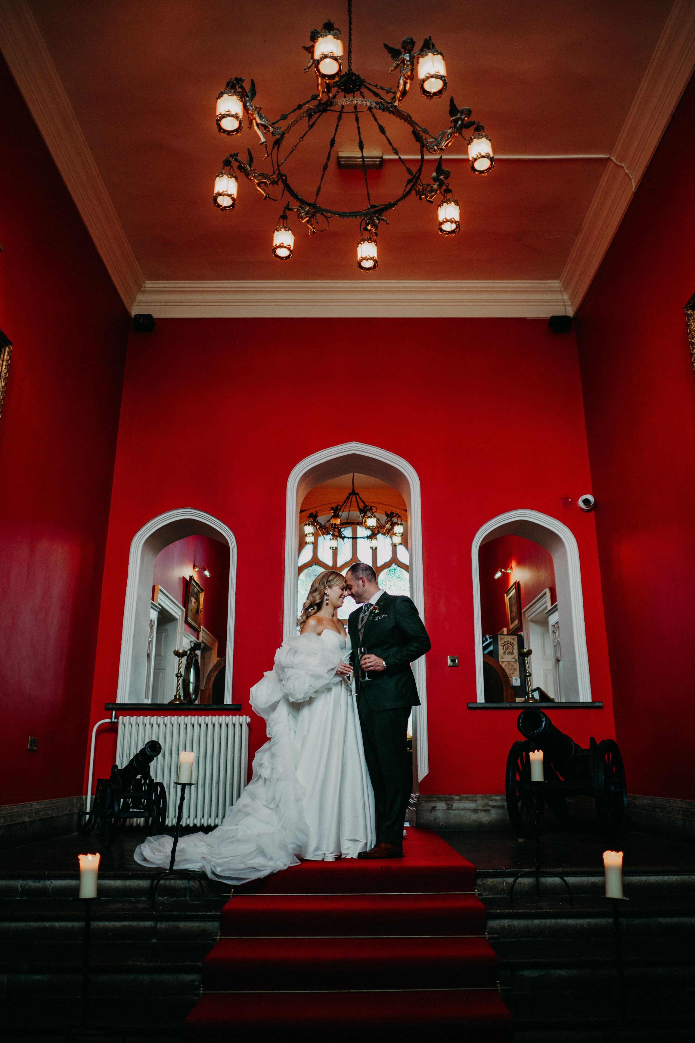 Bride and groom celebrating together beneath dramatic red interiors after an intimate wedding in Ireland