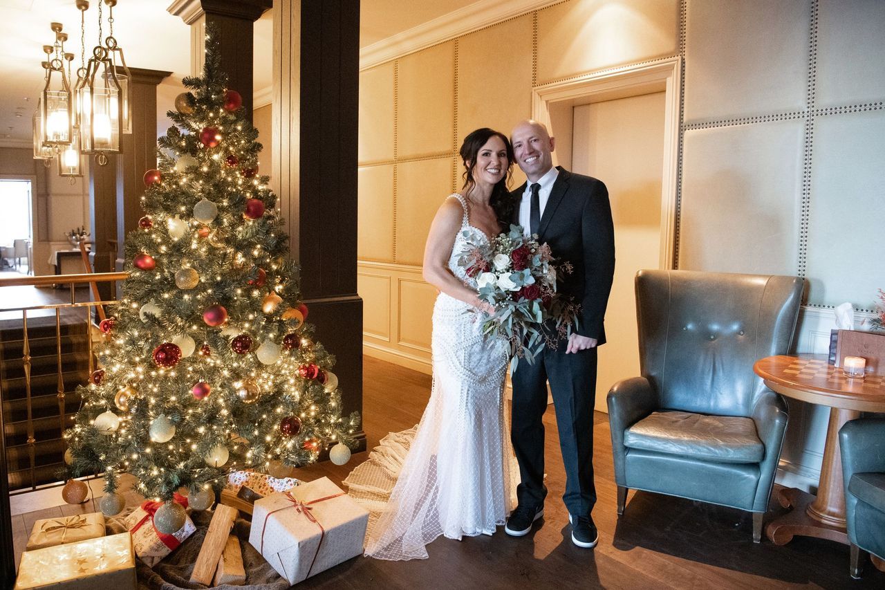 Bride and groom in a lobby of the hotel with a lighted Christmas tree on the side