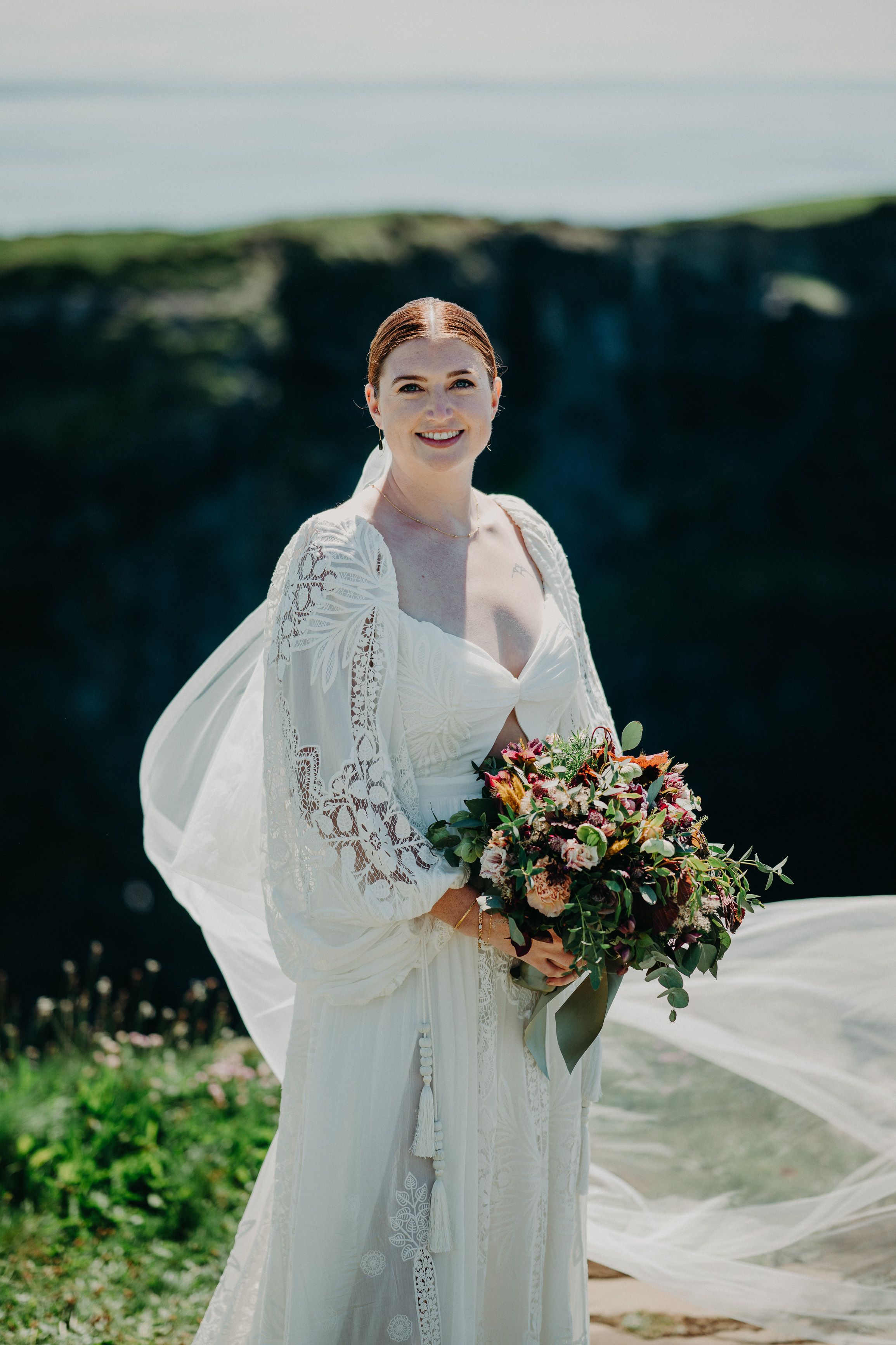 A bride looking radiant wearing a white gown and holding a bouquet during her small wedding in Ireland