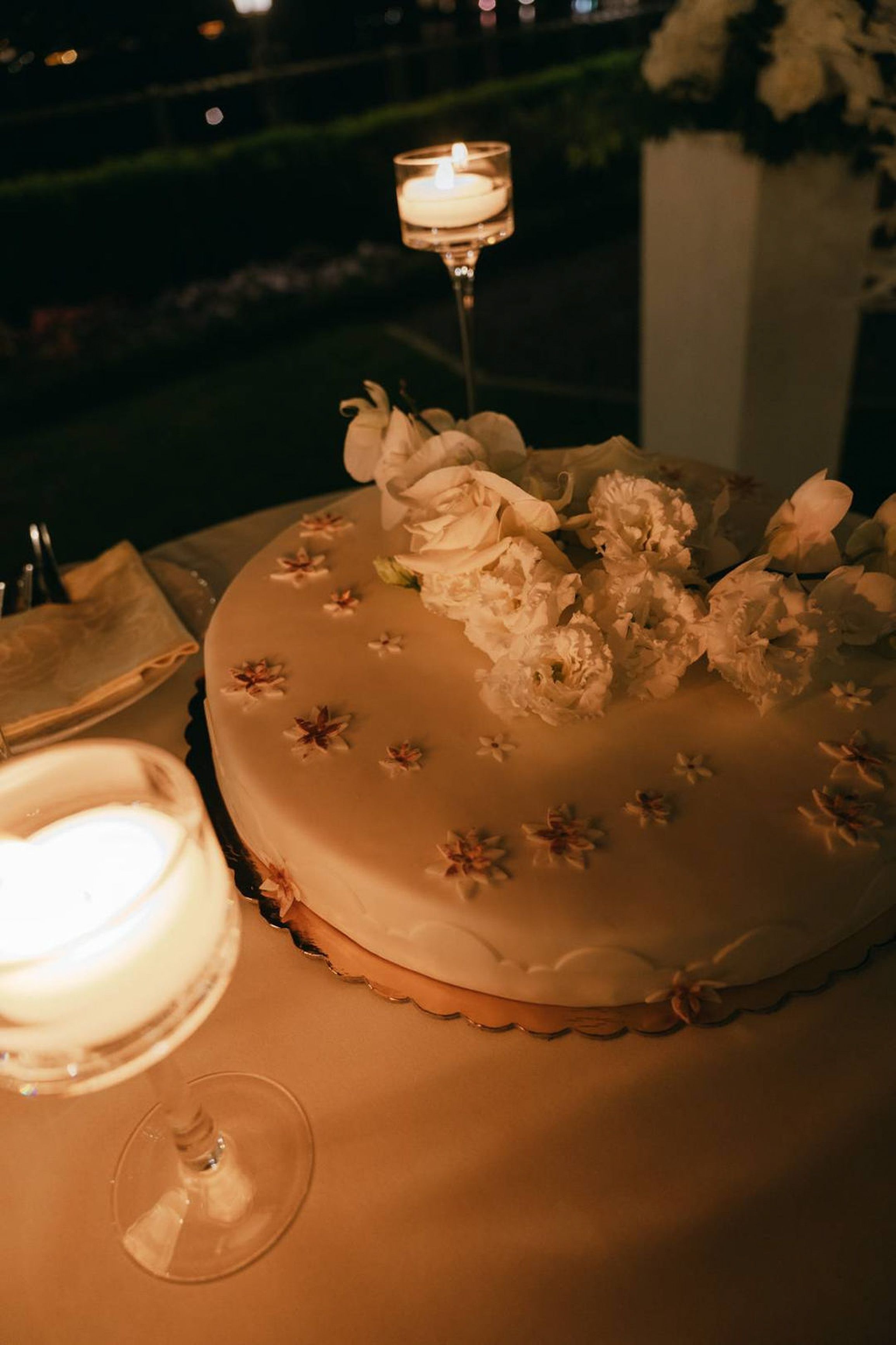 Floral wedding cake illuminated by candlelight at a small wedding in Italy reception