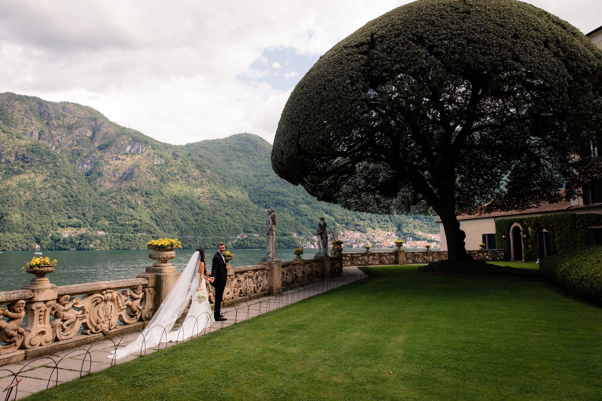Newlyweds holding each other's hands while walking at a park overlooking Lake Como for their destination wedding in Italy.