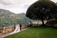 Newlyweds holding each other's hands while walking at a park overlooking Lake Como for their destination wedding in Italy.