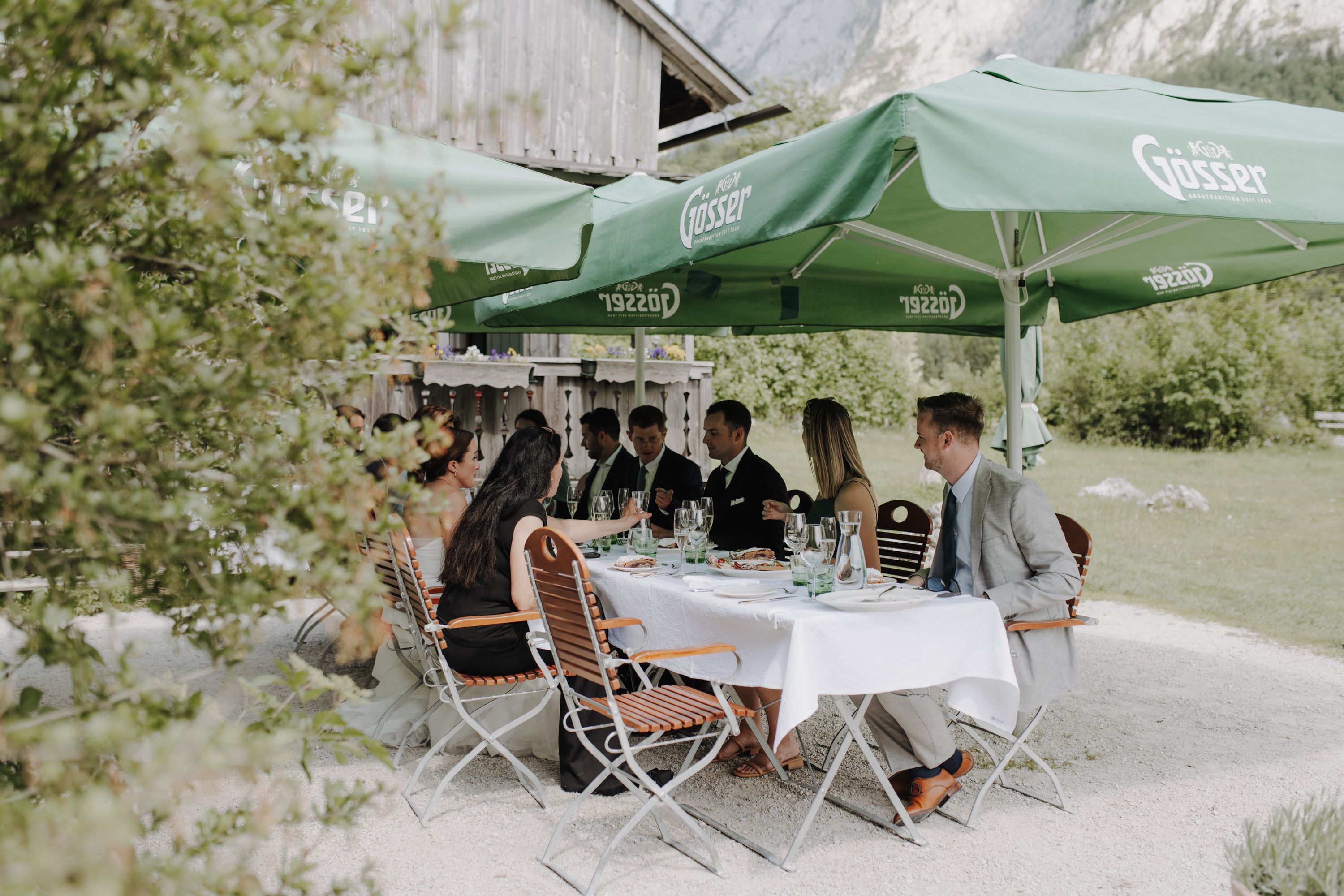 Wedding party sharing lunch under umbrellas at a mountain inn in Austria