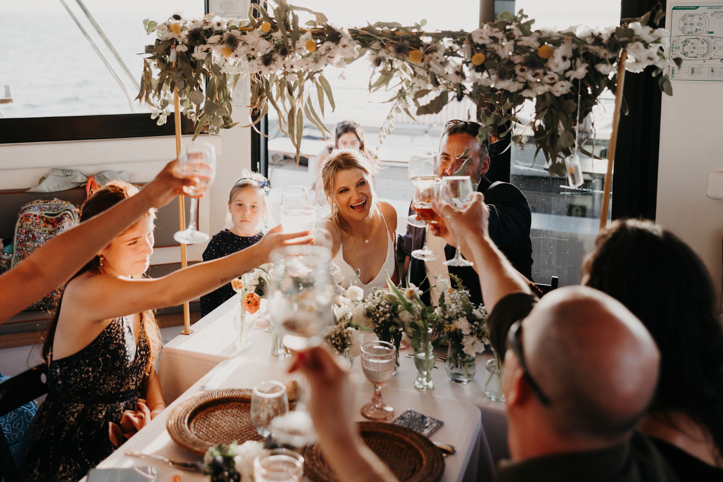 Bride and groom having a toast with their guests inside a boat during the reception of their destination wedding in Portugal