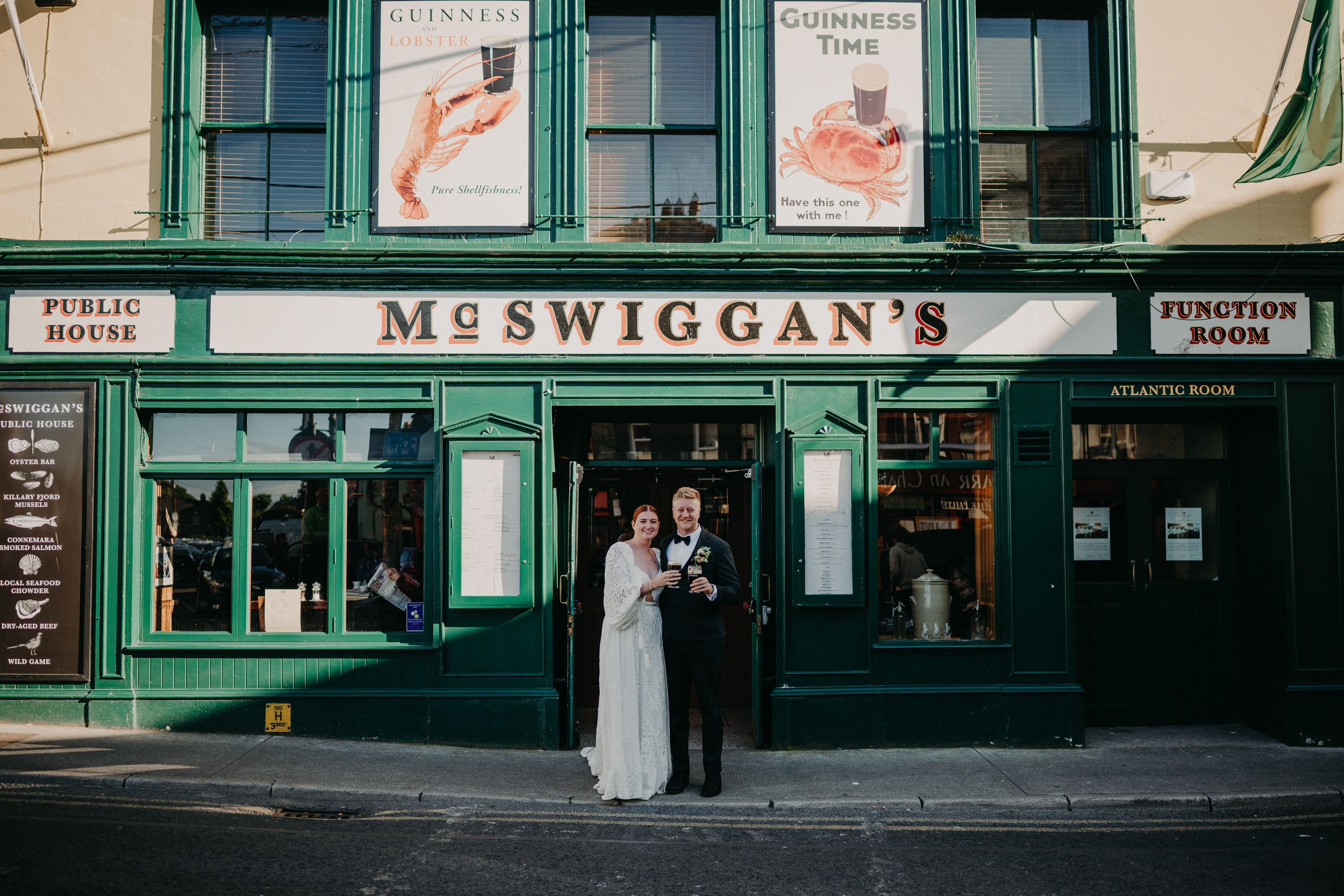 A groom and bride standing in front of a bar after their small wedding in Ireland