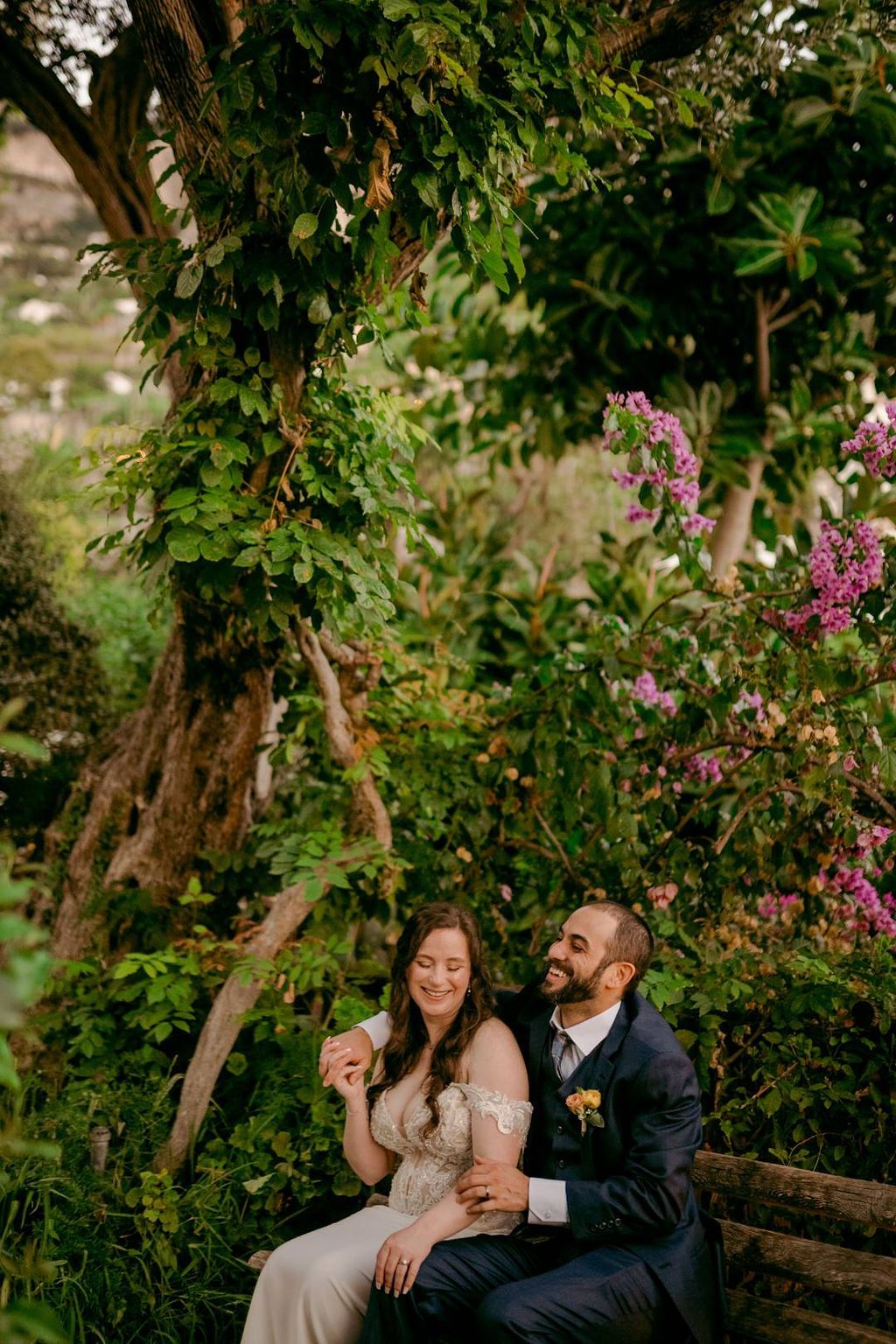 Newlyweds laughing during the photoshoot of their elopement in Italy, with lush greens in the background