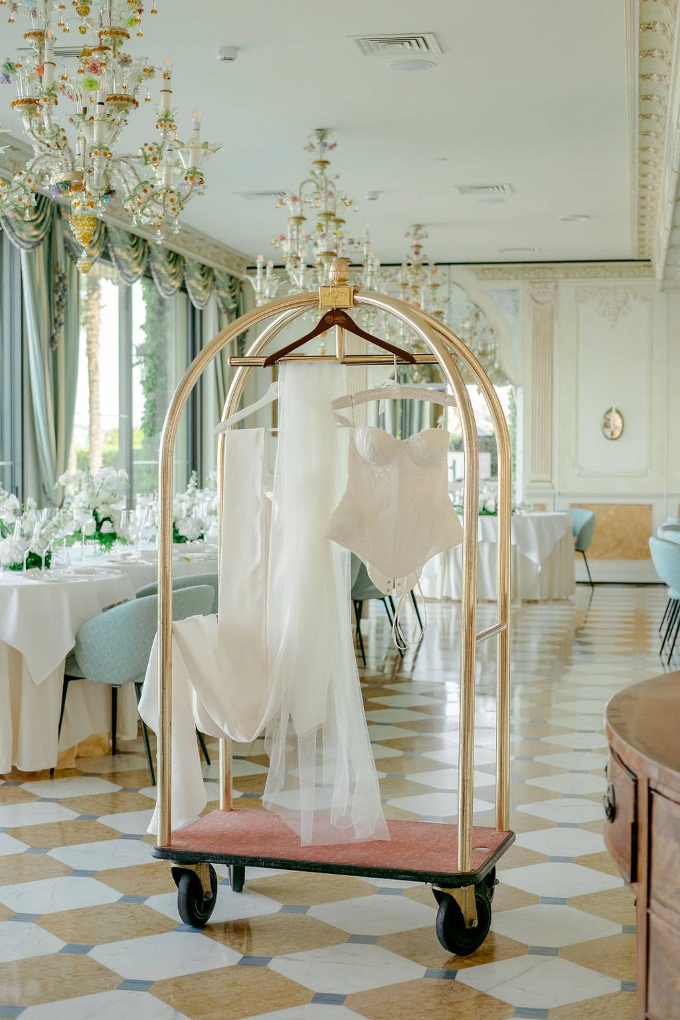 Elegant wedding dress and veil displayed in a luxury reception space before a small wedding in Italy
