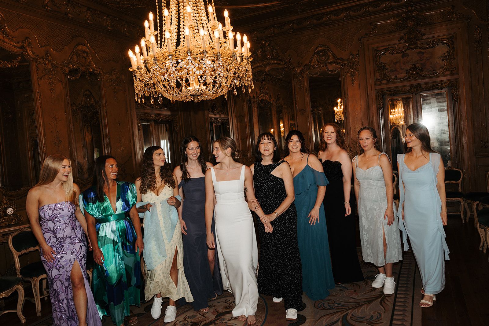 Bride in a wedding dress with her bridesmaids inside a palace room with exquisite chandelier in Portugal