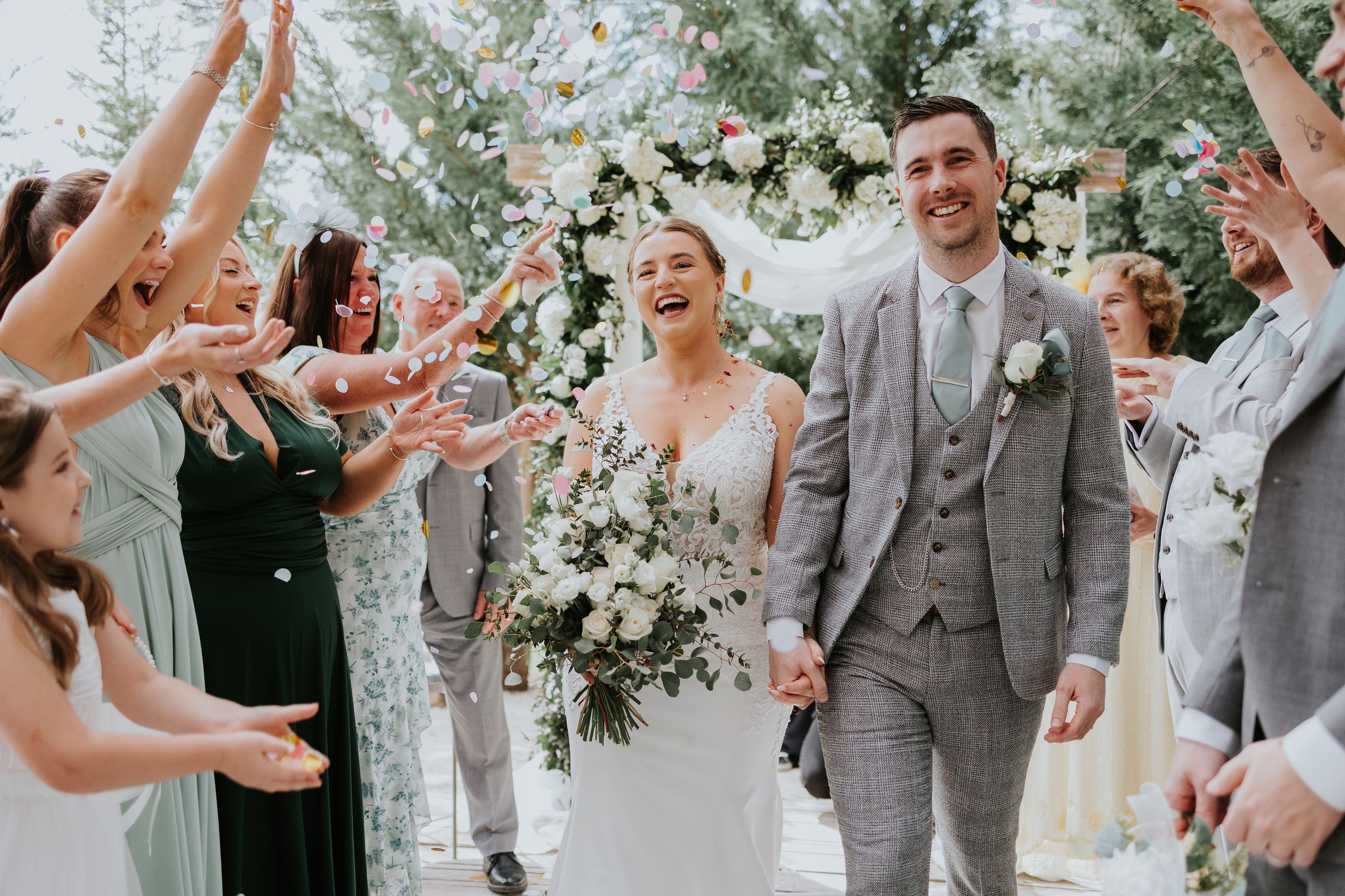 Bride and groom walk down the aisle happily while their guests threw white petals on them