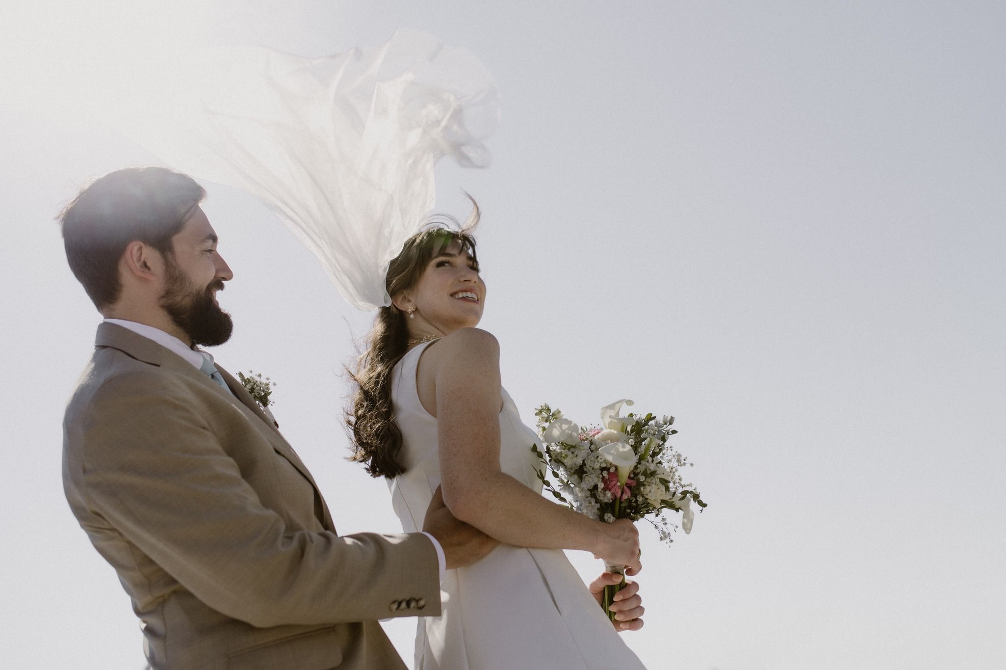 Groom and bride with a veil in the wind