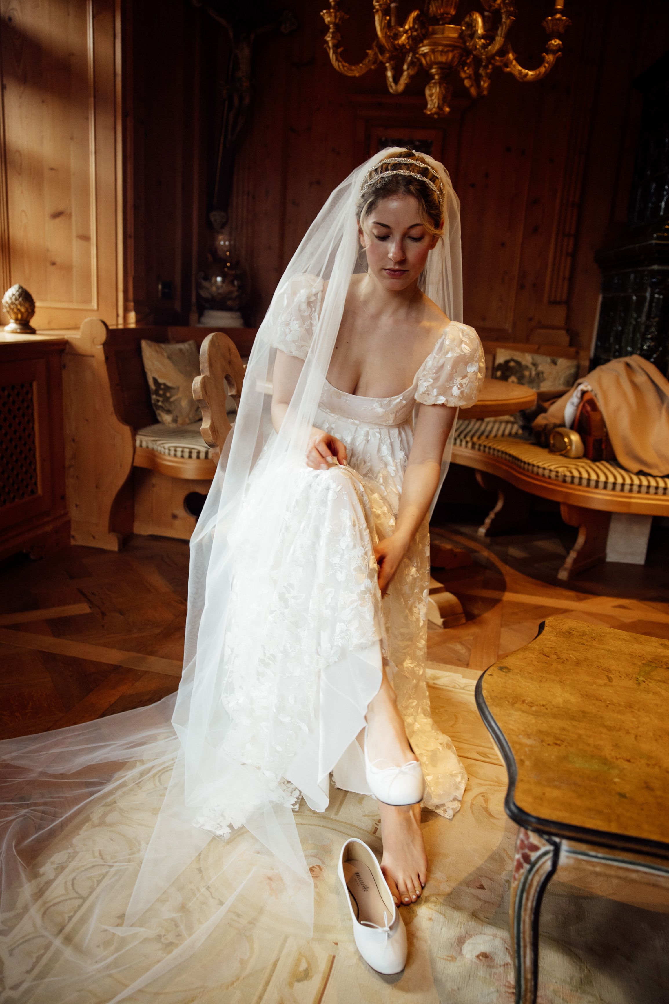 Bride putting on wedding shoes in a charming alpine room before a small wedding in Austria