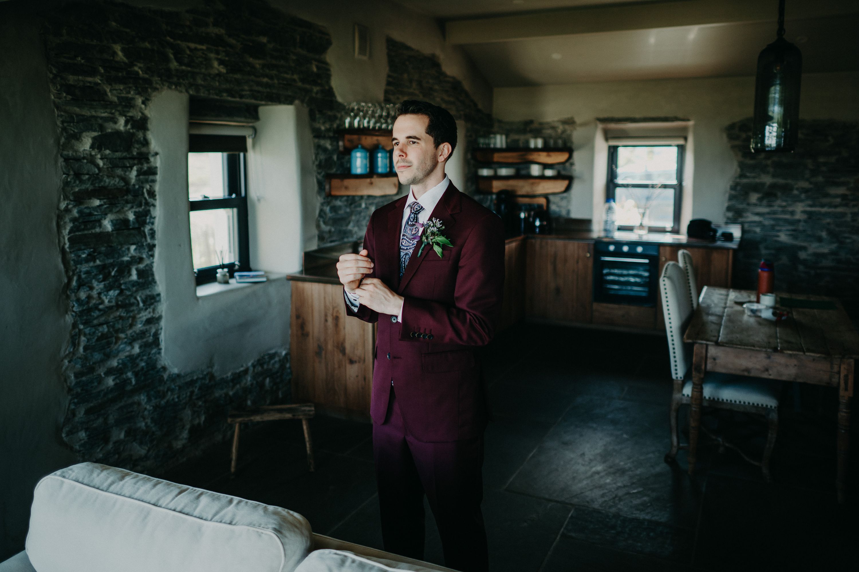 A groom wearing a purple suit inside a cottage preparing for his small wedding in Ireland
