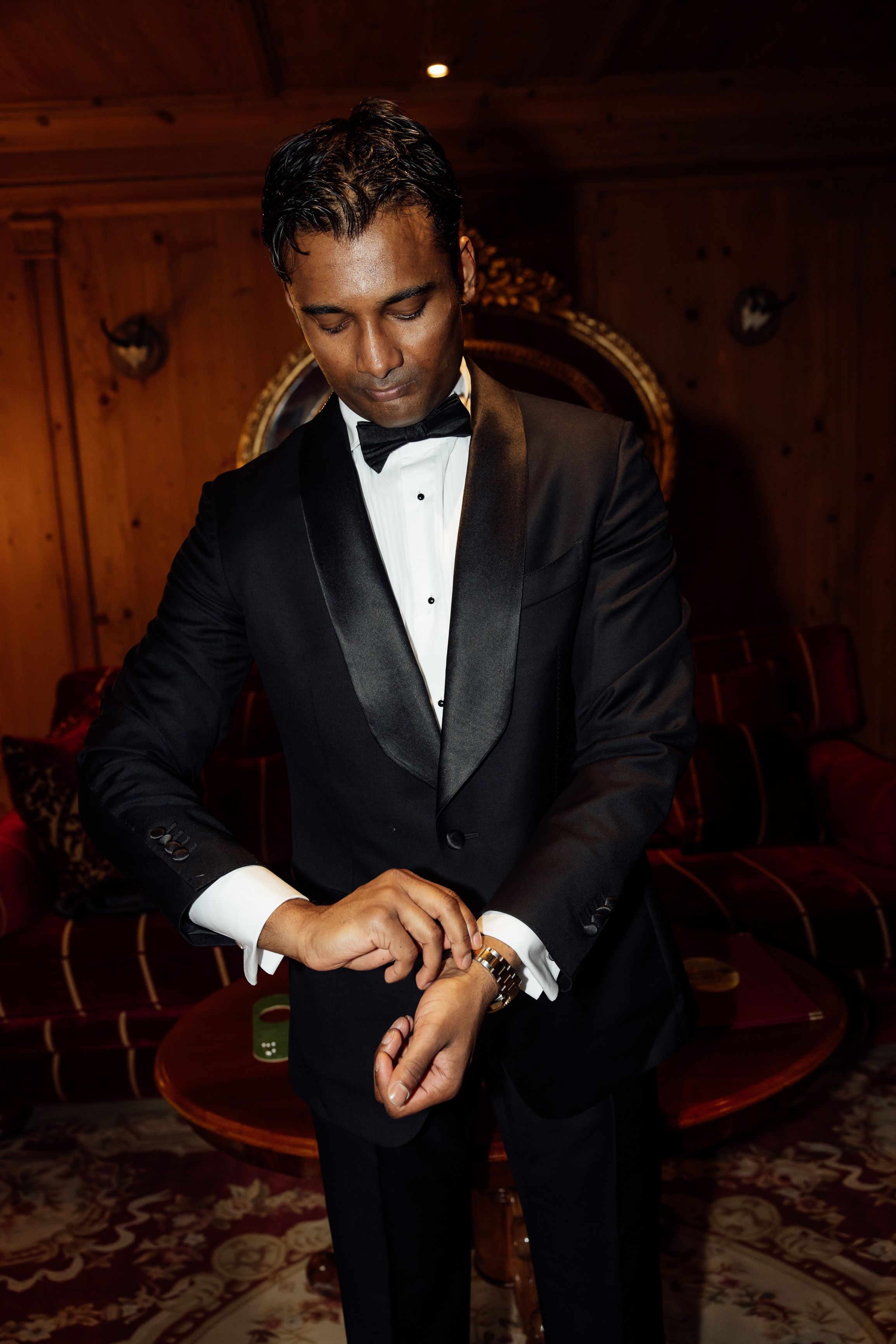 Groom fastens his watch while getting ready in a cozy alpine lodge for an intimate wedding in Austria