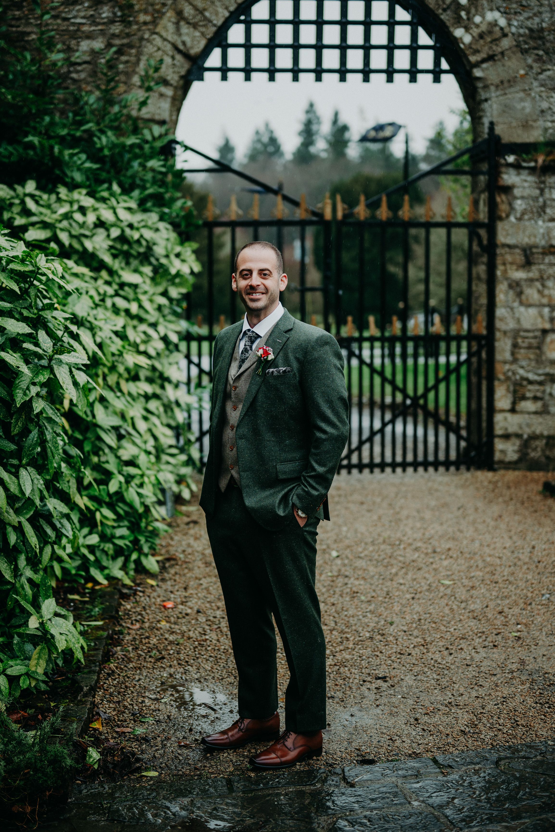 Groom posing beneath the castle gate before an intimate wedding in Ireland