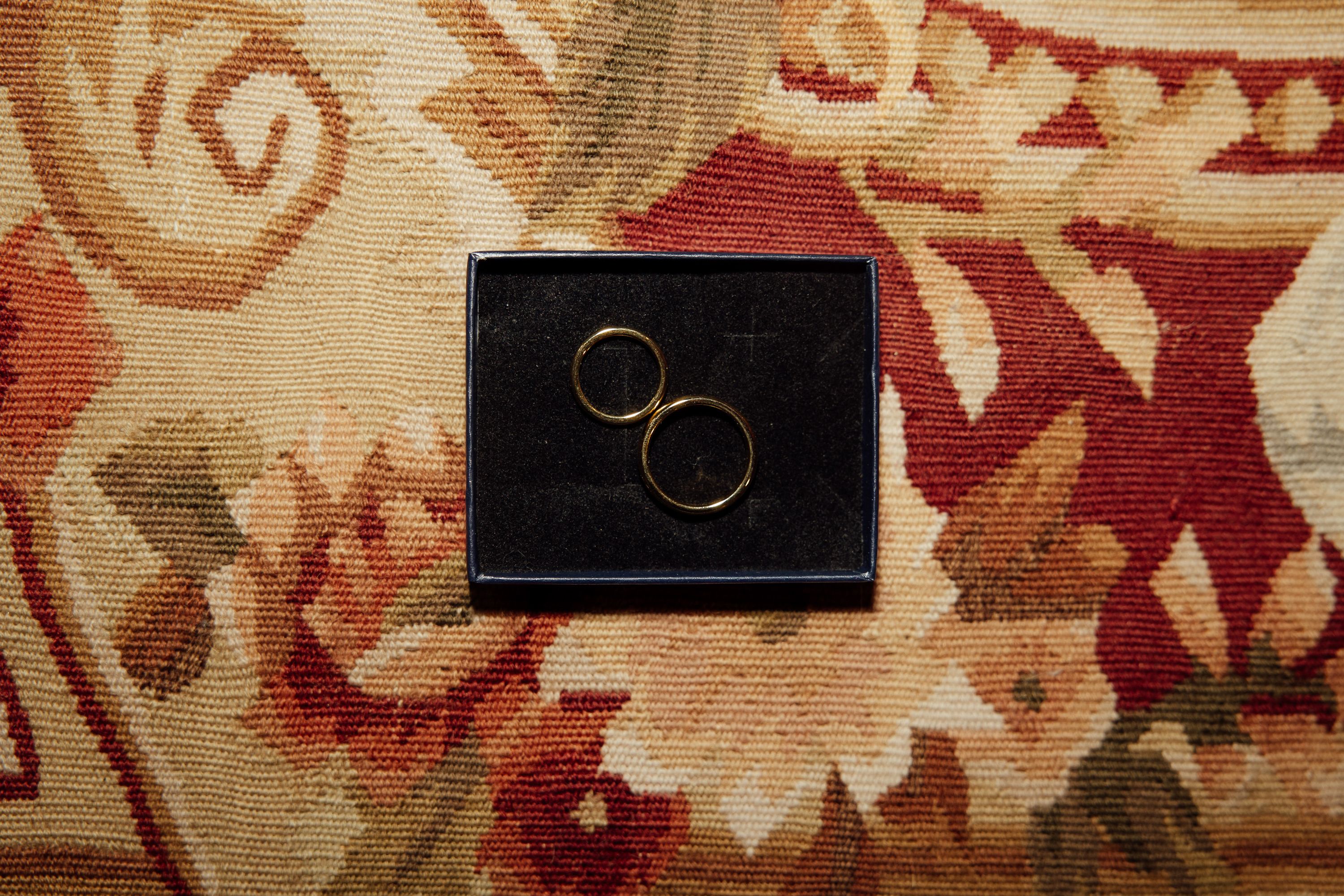 Wedding rings displayed in a box on a patterned rug for an intimate wedding in Austria