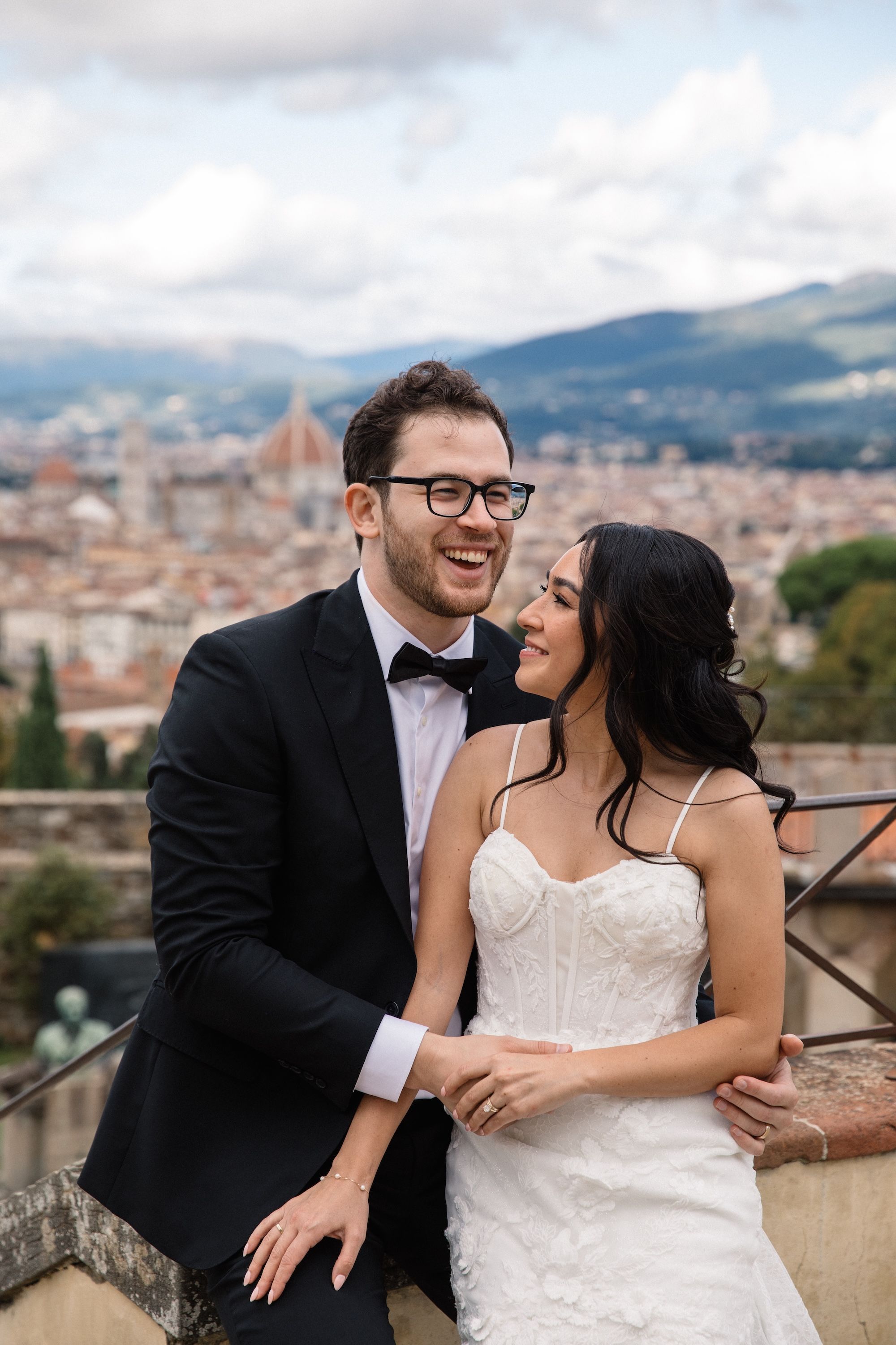 Newlyweds talk to each other during their photoshoot with the Florence skyline in the background