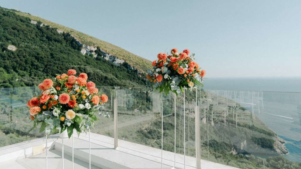 Floral arrangement of orange shades serve as decor atop a terrace of a hotel in Sorrento for an Italian small wedding