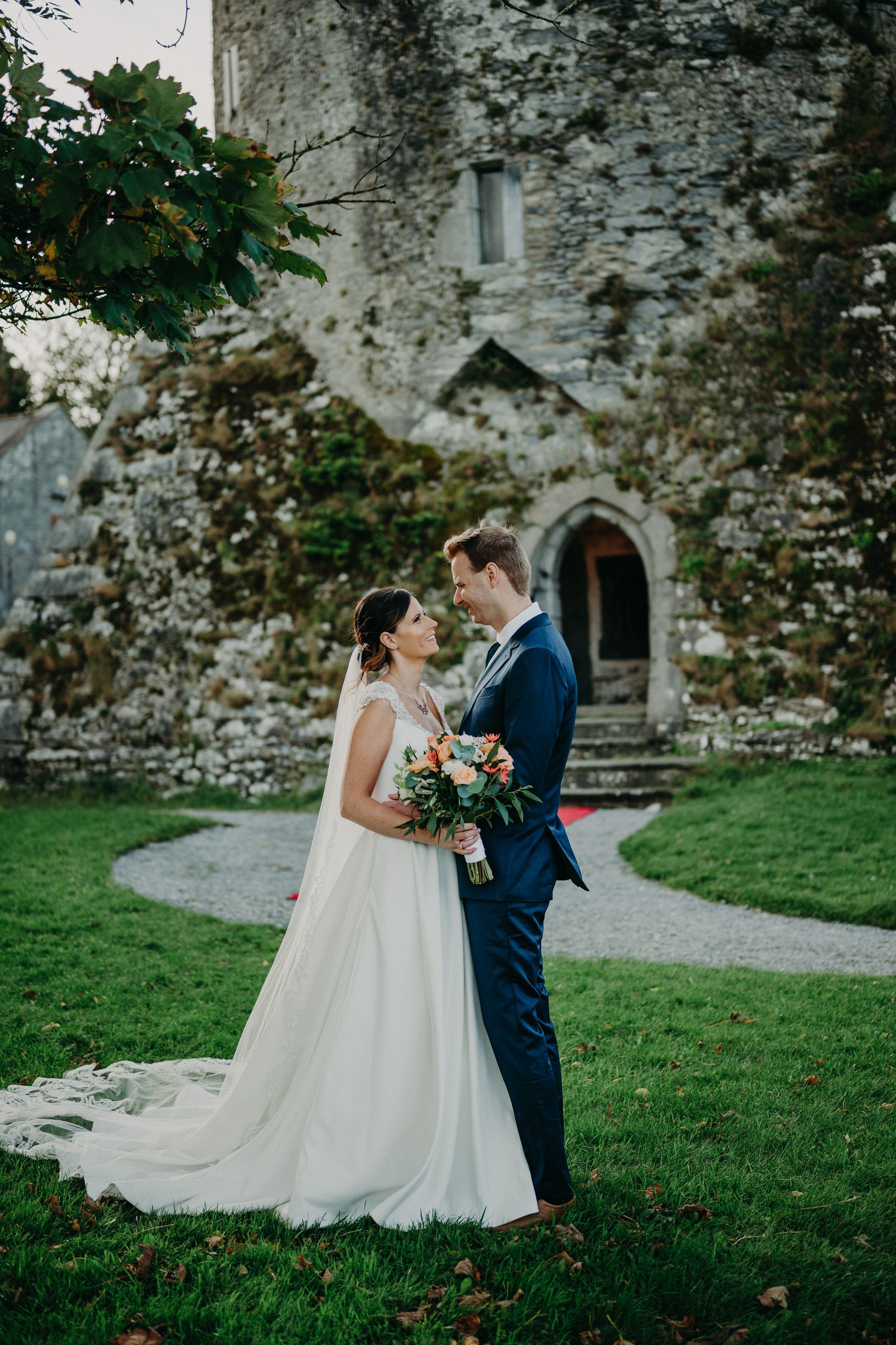 Bride and groom sharing a romantic moment in front of a medieval castle during an intimate wedding in Ireland.