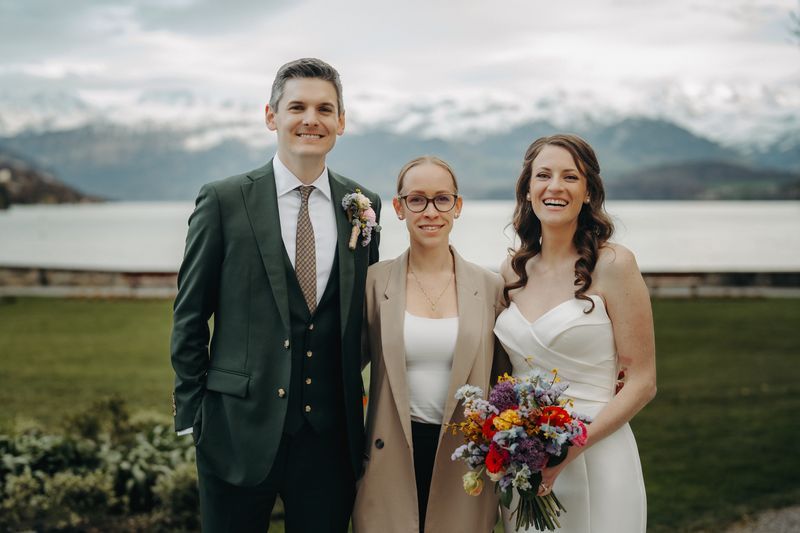 Destination wedding planner in Switzerland posing with bride and groom in front of a lake