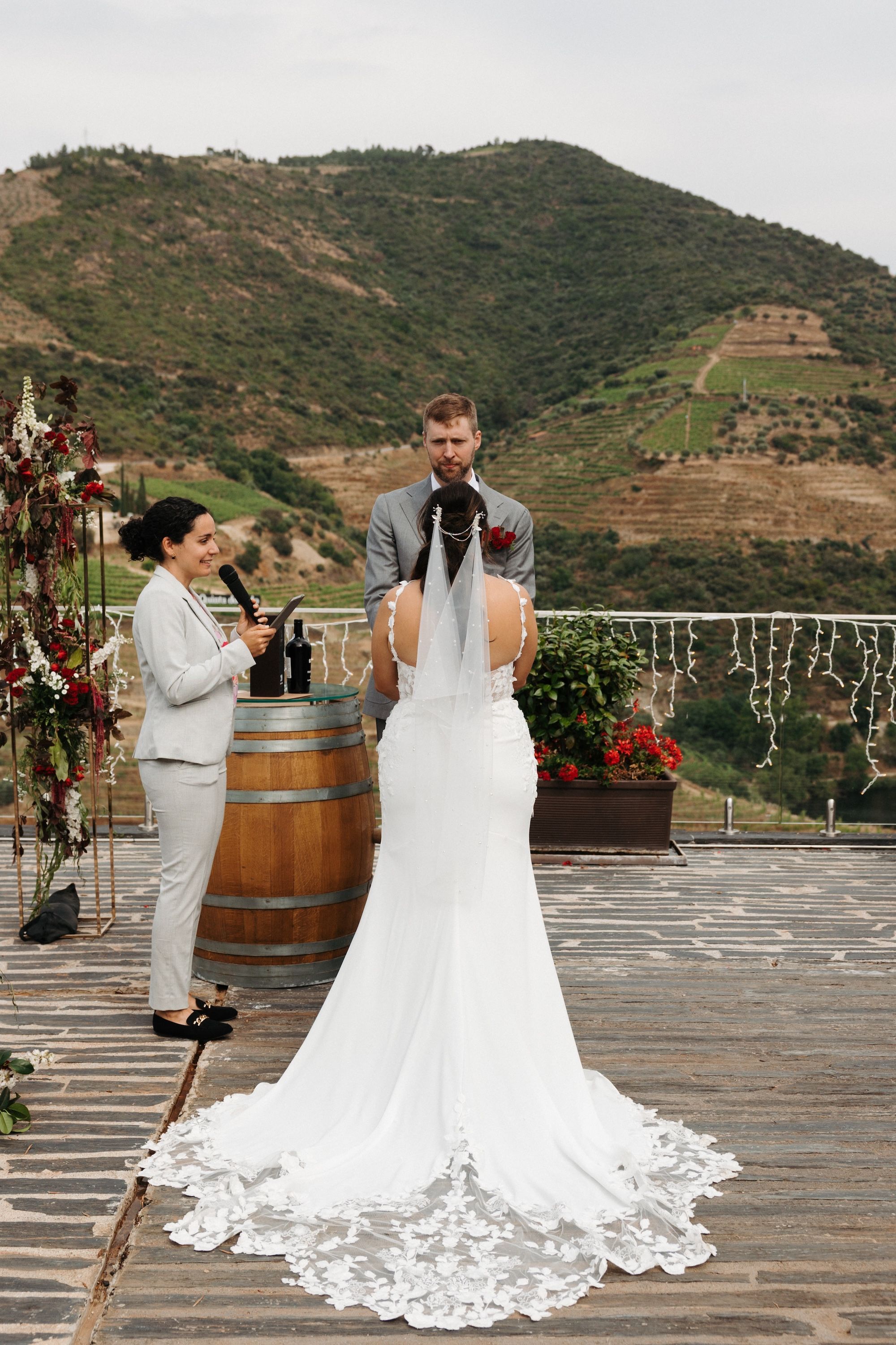 Couple holds hands during the ceremony of their micro wedding in Portugal with mountains and vineyards in the background