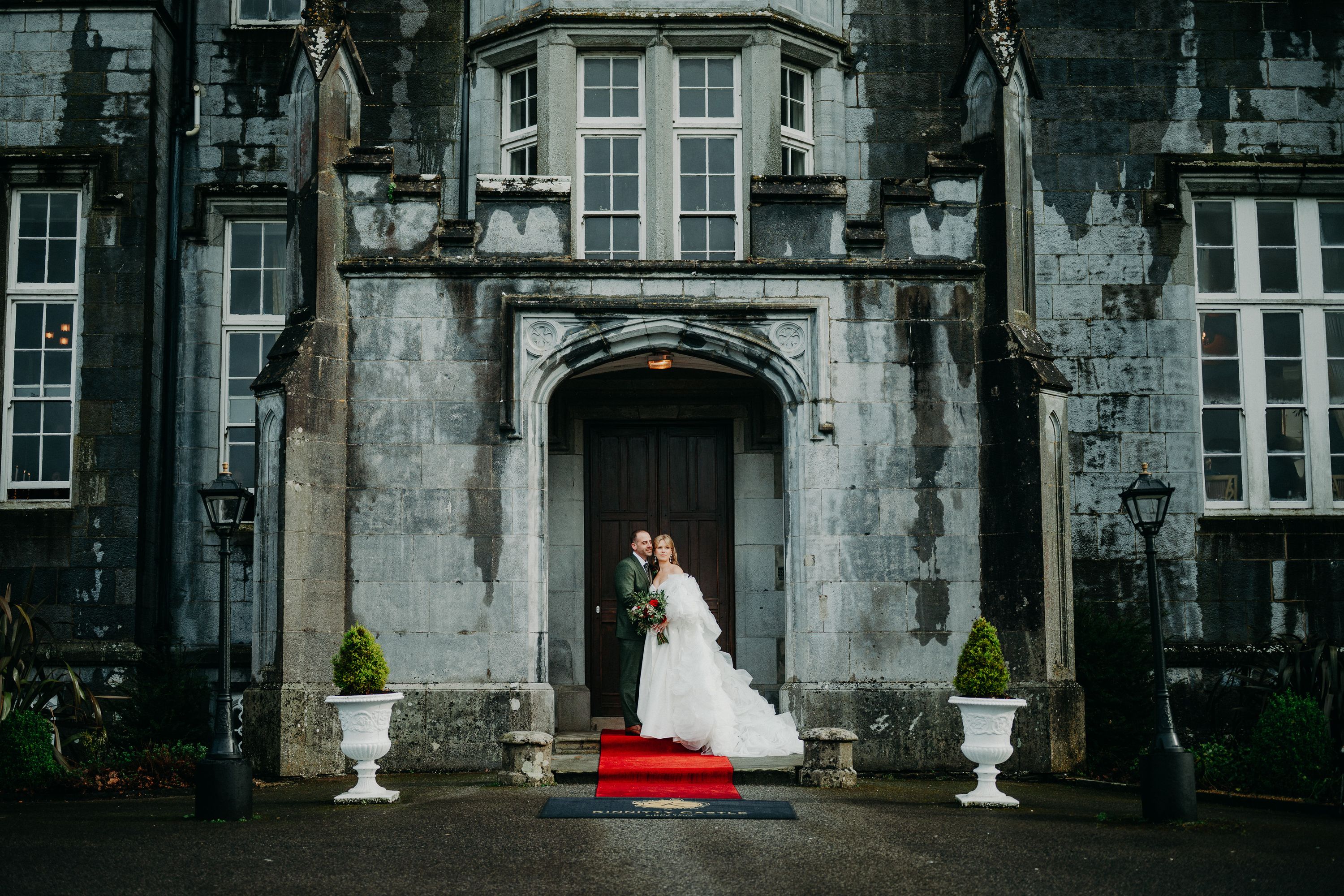 Newlyweds standing beneath the grand castle entrance after a small wedding in Ireland