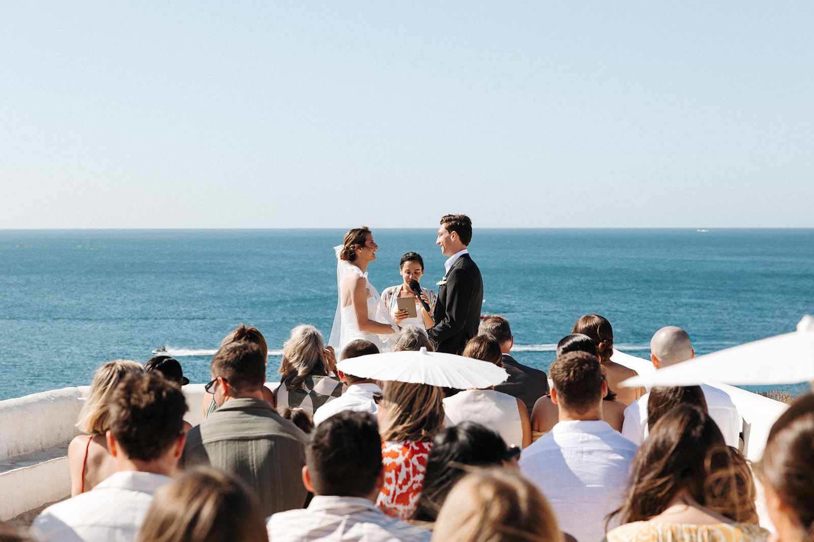 Bride and groom reciting vows atop a cliff with the Algarve coastline in the background