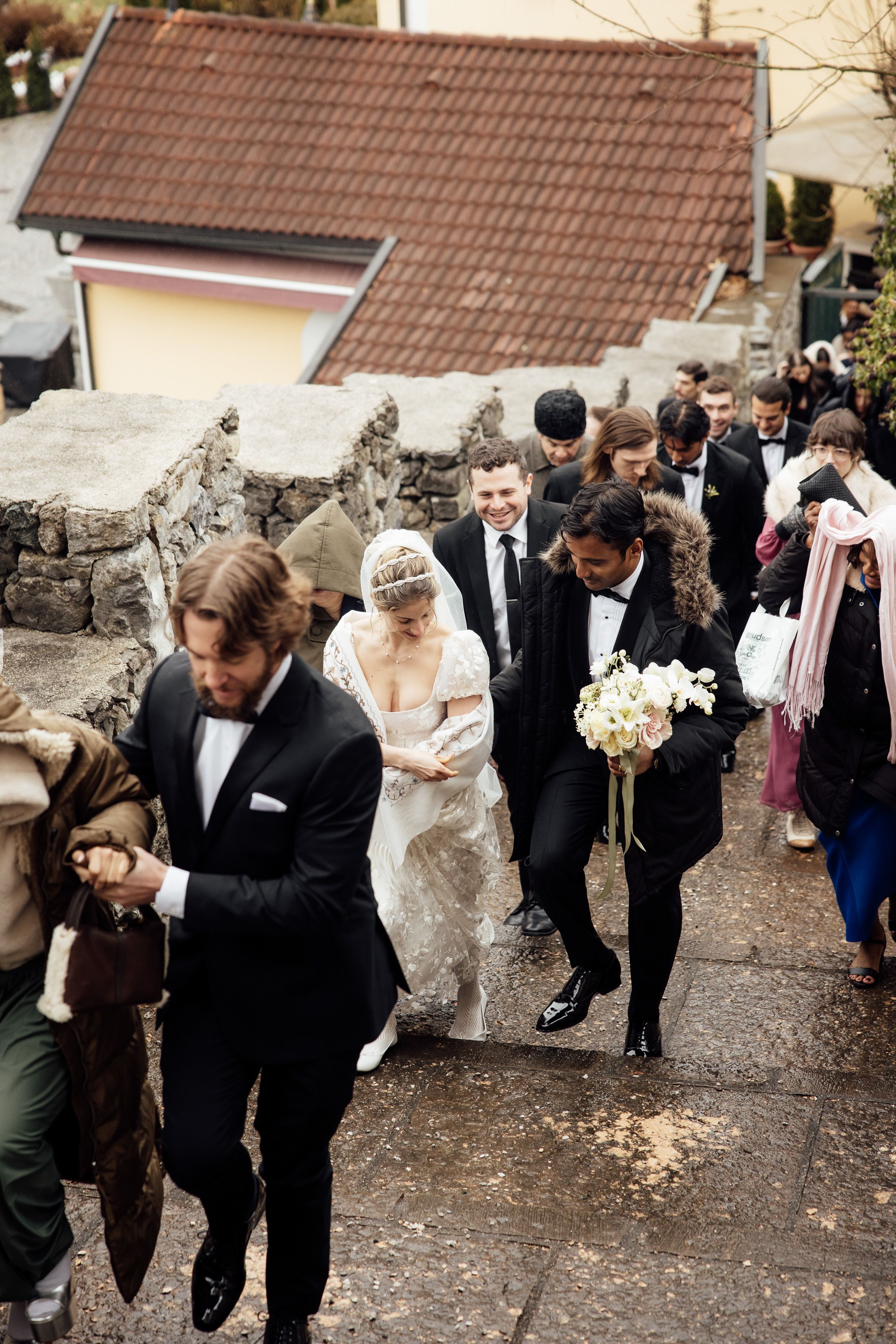 Wedding guests and newlyweds walk up castle steps following the ceremony at an intimate wedding in Austria