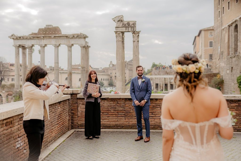 Groom and celebrant looking at the bride as she enters the terrace for their elopement ceremony in Italy