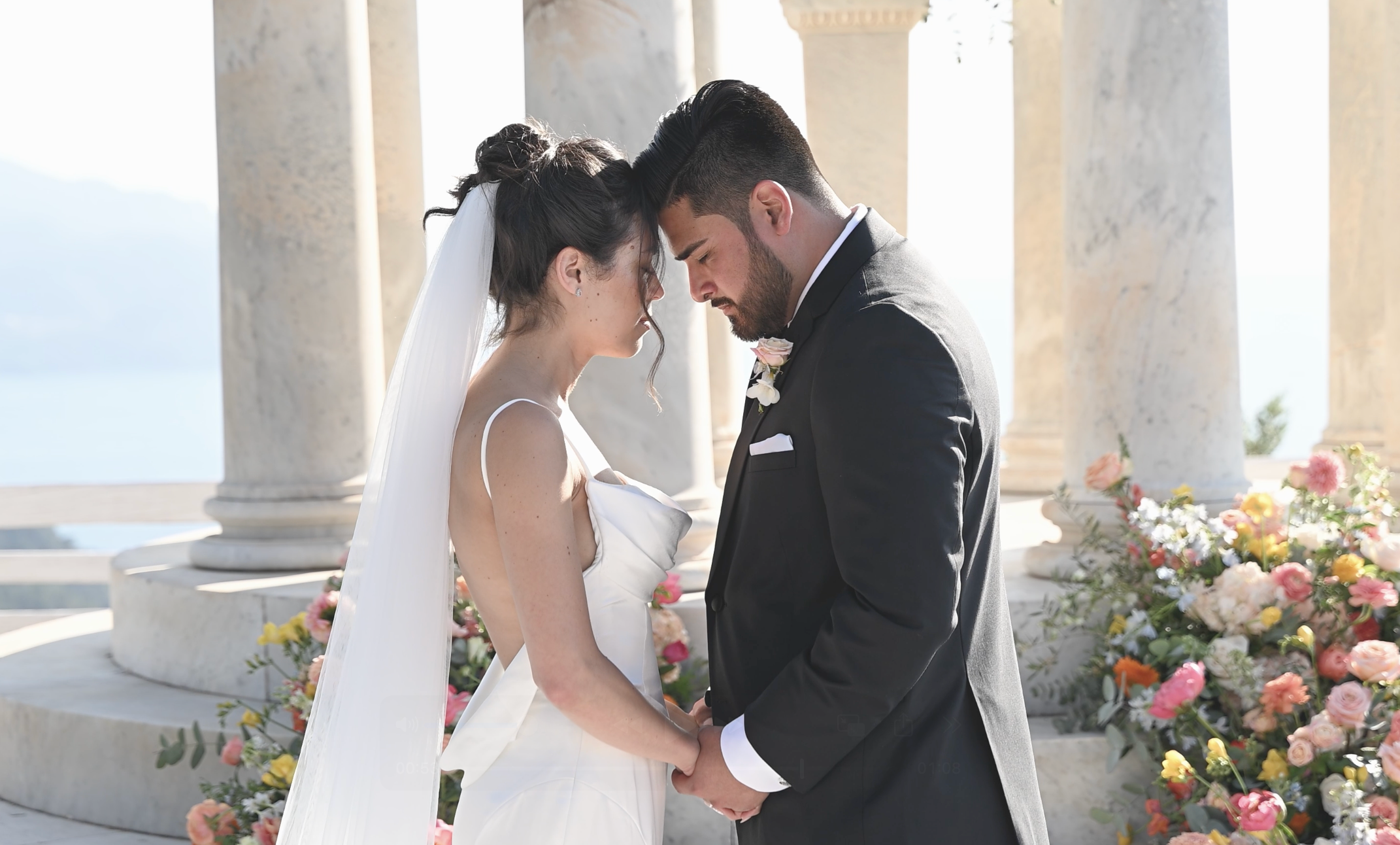 Bride and groom with heads together and a white stone gazebo in the background during their destination wedding in Spain